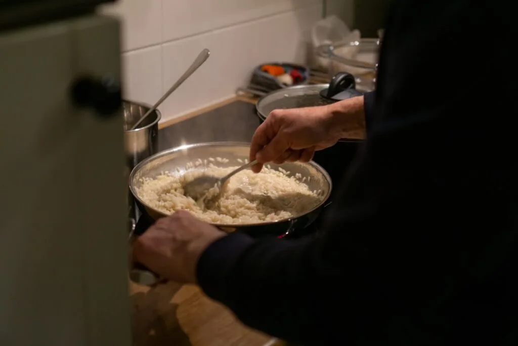 Mains remuant un risotto crémeux dans une grande poêle