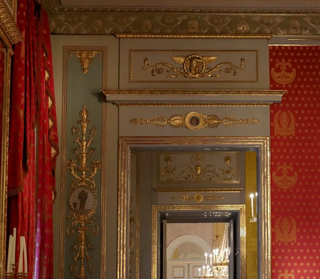 Portail intérieur doré avec moulures et tentures rouges au Palazzo Reale