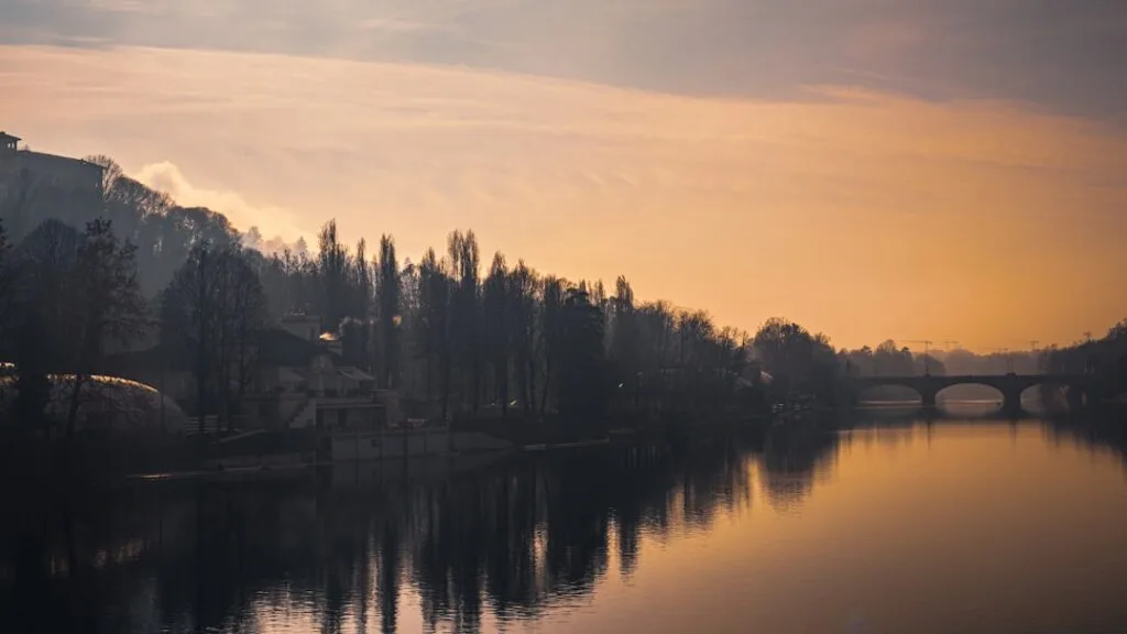 Reflets orangés du fleuve Po à Turin avec arbres alignés
