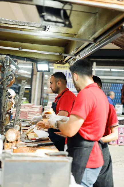 Marchands en polos rouges découpent charcuterie dans un marché turinois
