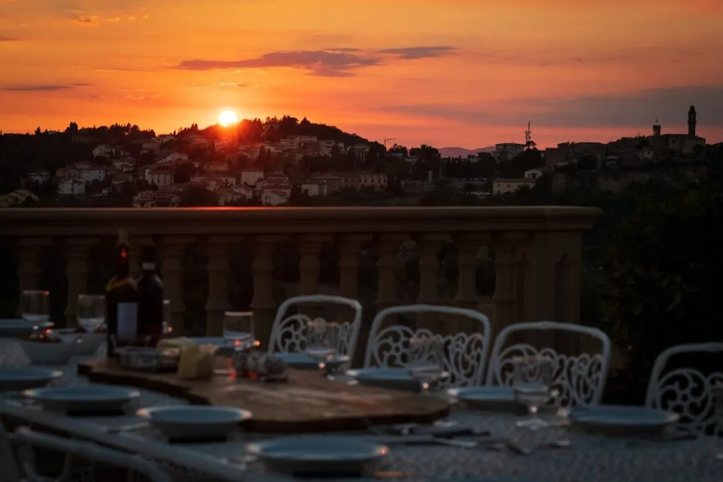 Table dressée sur terrasse au coucher de soleil, collines en arrière-plan